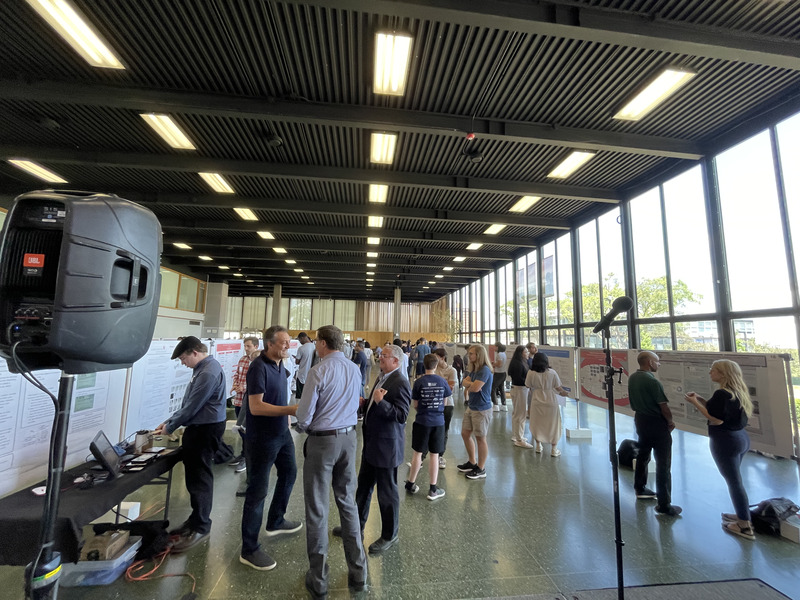 Photo showing people in an event hall where students' research posters are arrayed.